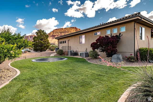 373 W Meridian Dr, Ivins, UT 84738 - rear view of property featuring a lawn, central AC, a mountain view, and stucco siding