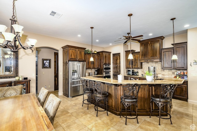 373 W Meridian Dr, Ivins, UT 84738 - kitchen featuring appliances with stainless steel finishes, arched walkways, dark brown cabinets, tasteful backsplash, and recessed lighting