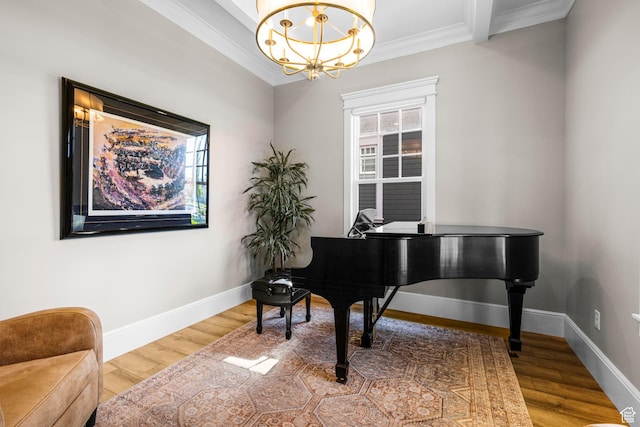 living area with ornamental molding, a chandelier, wood finished floors, and baseboards