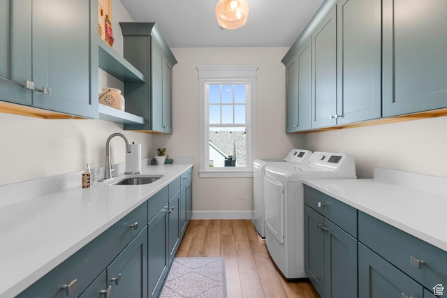 laundry room with independent washer and dryer, cabinet space, baseboards, and light wood finished floors