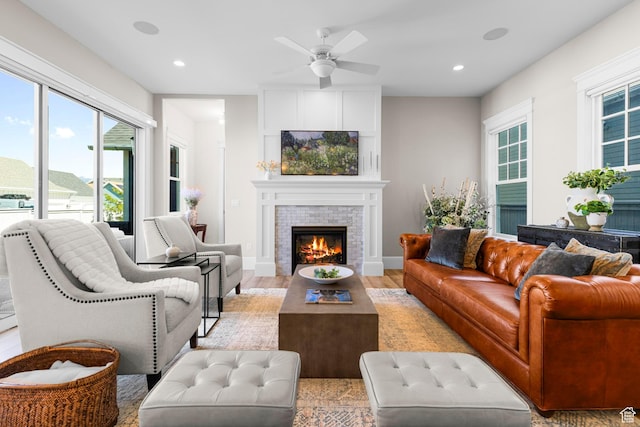 living area featuring healthy amount of natural light, a ceiling fan, a tiled fireplace, light wood finished floors, and recessed lighting