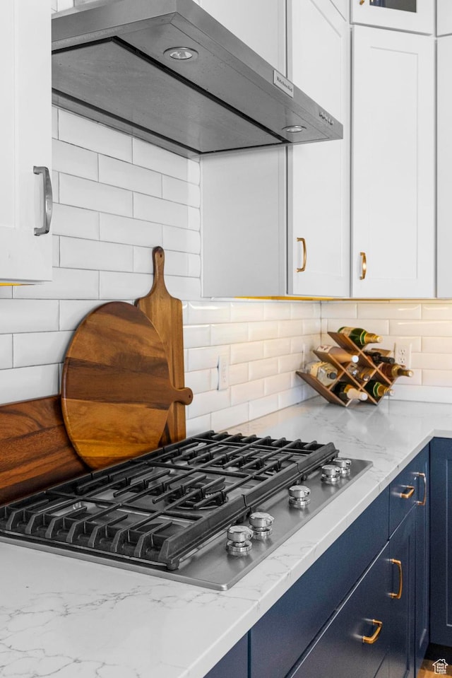 kitchen featuring stainless steel gas cooktop, ventilation hood, blue cabinetry, and white cabinets