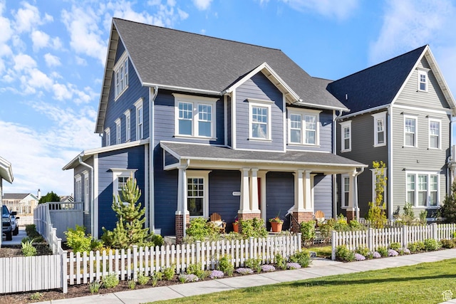 view of front of home with a porch, a fenced front yard, and a shingled roof