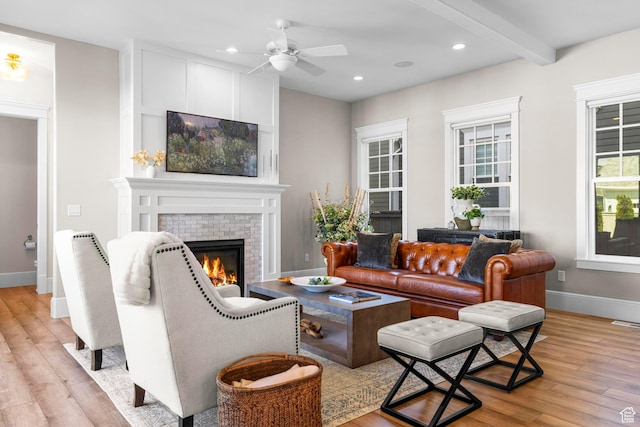 living area with light wood finished floors, a glass covered fireplace, baseboards, ceiling fan, and recessed lighting