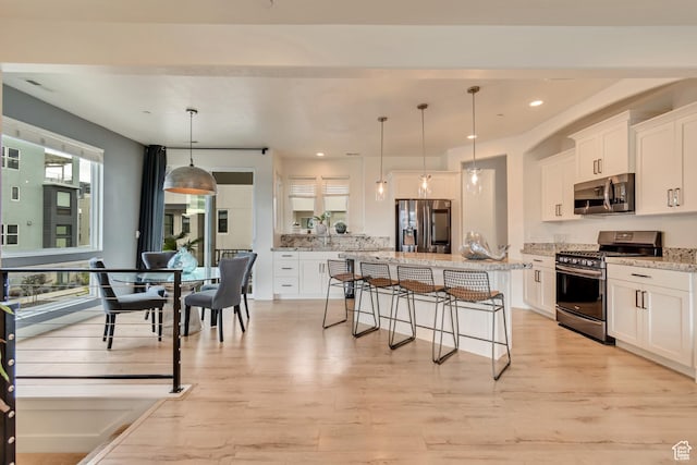 11233 S Clear Blue Dr Unit 402, South Jordan, UT 84009 - kitchen featuring appliances with stainless steel finishes, a breakfast bar area, white cabinets, a center island, and hanging light fixtures
