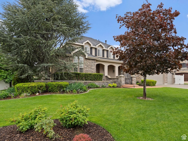traditional-style house featuring stone siding, driveway, a front yard, stucco siding, and an attached garage