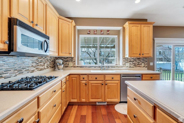 kitchen featuring appliances with stainless steel finishes, a sink, light brown cabinetry, light countertops, and recessed lighting