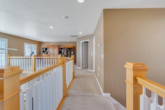 hallway featuring an upstairs landing, baseboards, light carpet, and recessed lighting