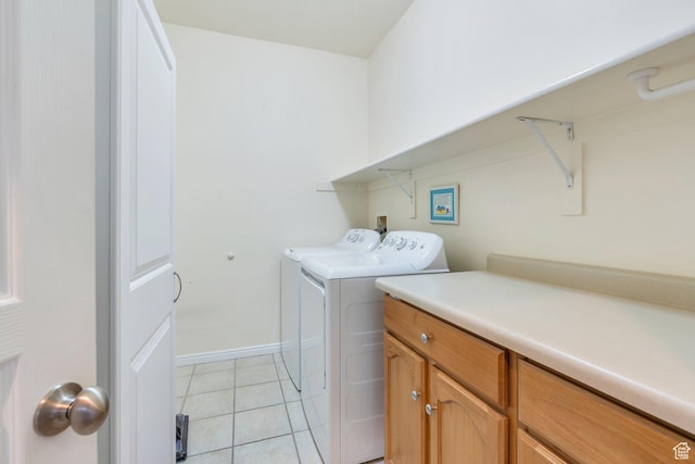washroom with washer and clothes dryer, light tile patterned flooring, baseboards, and cabinet space
