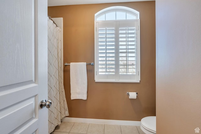 full bathroom with baseboards, plenty of natural light, tile patterned floors, and toilet