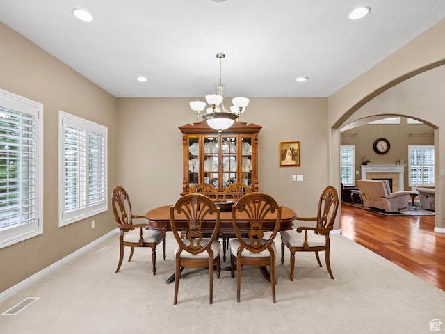 dining space with a chandelier, arched walkways, plenty of natural light, light carpet, and recessed lighting