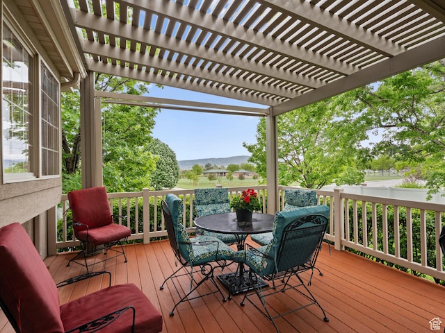 wooden deck featuring outdoor dining area, a pergola, and a mountain view