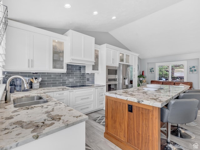 156 Crystal Bay Dr, Stansbury Park, UT 84074 - kitchen featuring appliances with stainless steel finishes, a sink, vaulted ceiling, a kitchen island, and a kitchen bar