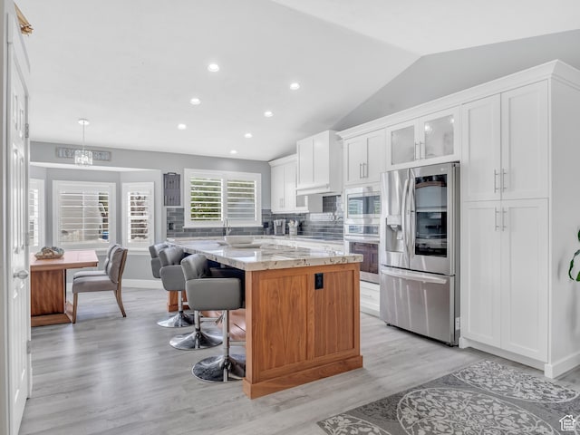 156 Crystal Bay Dr, Stansbury Park, UT 84074 - kitchen with appliances with stainless steel finishes, a center island, a kitchen breakfast bar, white cabinets, and tasteful backsplash