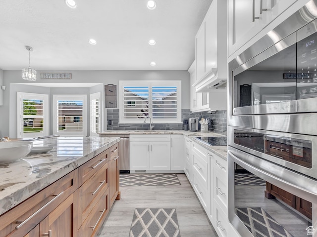 156 Crystal Bay Dr, Stansbury Park, UT 84074 - kitchen with light wood-type flooring, recessed lighting, tasteful backsplash, light stone counters, and white cabinetry