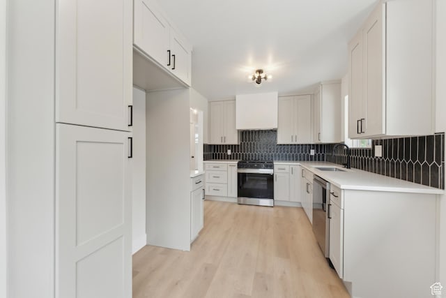 kitchen with electric range, stainless steel dishwasher, a sink, backsplash, and light wood-type flooring