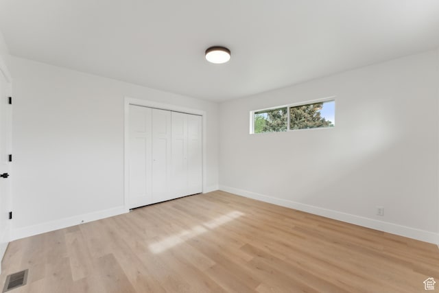 unfurnished bedroom featuring baseboards, light wood-style flooring, and a closet