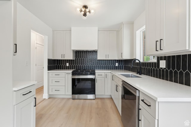 kitchen featuring black gas range, dishwasher, a sink, light wood-style flooring, and backsplash