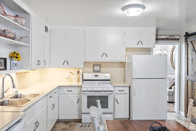 kitchen with white appliances, a sink, white cabinetry, a barn door, and light countertops