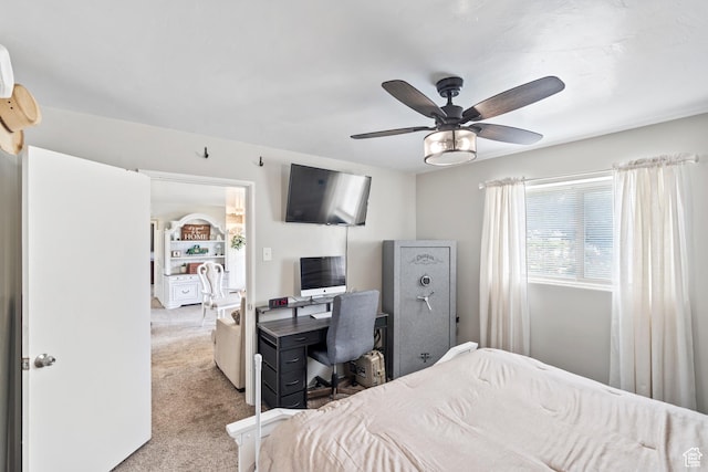 bedroom with light carpet, a ceiling fan, and an office area
