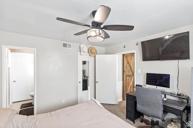 bedroom with light colored carpet, an office area, connected bathroom, and a ceiling fan