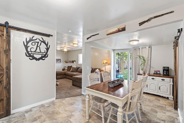 dining room featuring a barn door and baseboards