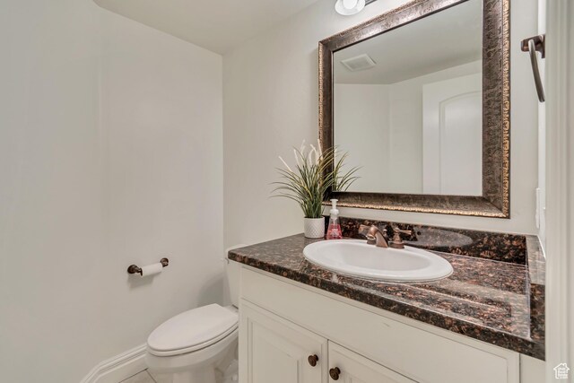 half bathroom featuring vanity and toilet