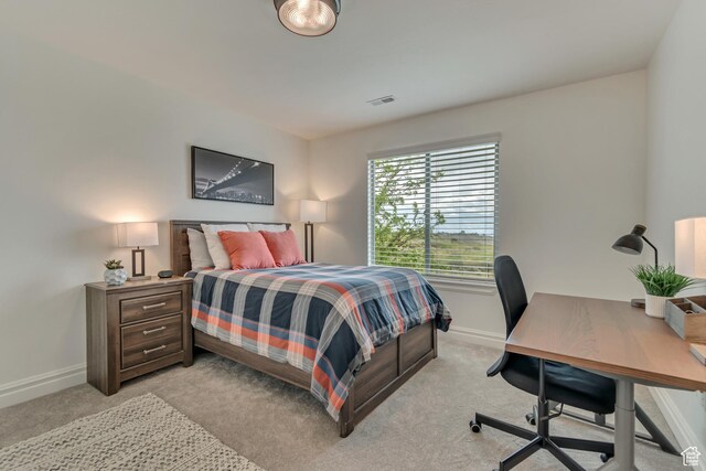 bedroom with baseboards, light carpet, and an office area