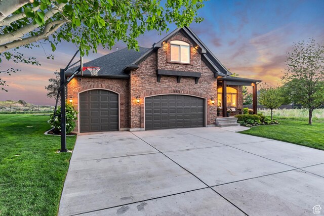 french provincial home with a front yard, concrete driveway, brick siding, and a garage