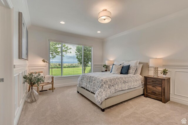 bedroom featuring a decorative wall, light carpet, ornamental molding, and a wainscoted wall