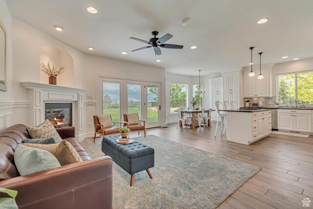 living area featuring a glass covered fireplace, recessed lighting, light wood finished floors, and a ceiling fan