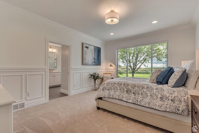 carpeted bedroom featuring crown molding, a decorative wall, ensuite bathroom, a wainscoted wall, and recessed lighting