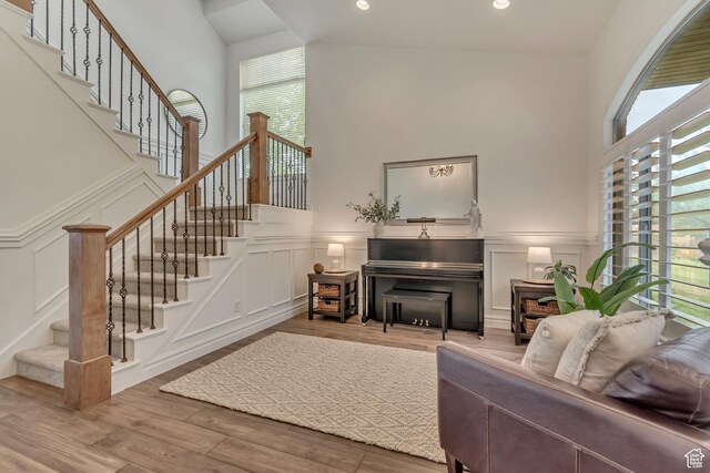 living area featuring a decorative wall, plenty of natural light, a high ceiling, stairway, and wood finished floors