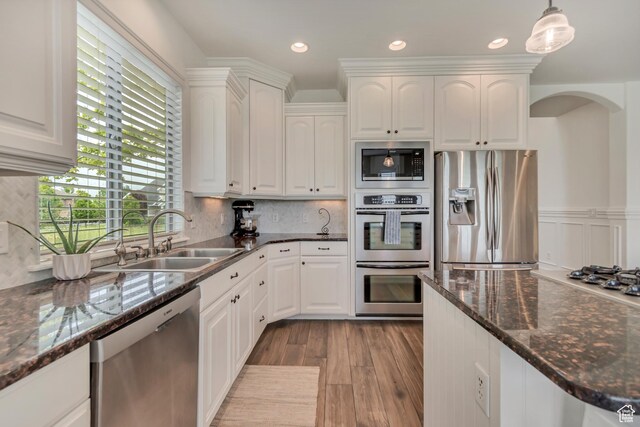 kitchen with stainless steel appliances, a sink, white cabinets, wood finished floors, and recessed lighting