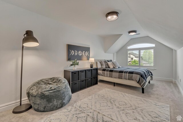bedroom featuring vaulted ceiling, light colored carpet, and baseboards