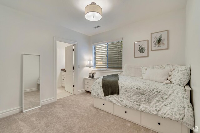 bedroom featuring light colored carpet, baseboards, and ensuite bathroom