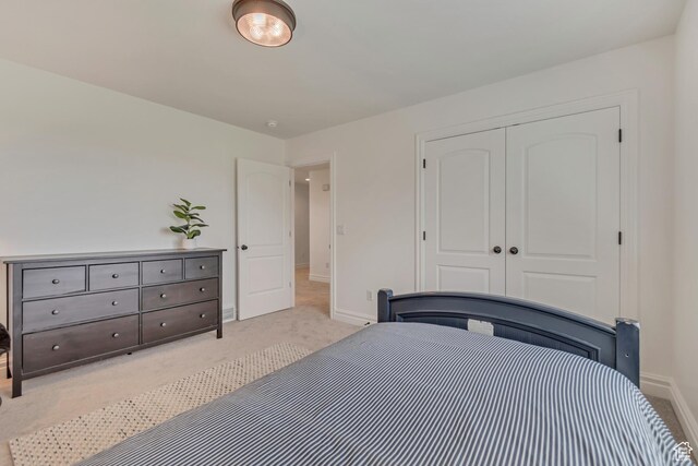 bedroom featuring light colored carpet, baseboards, and a closet