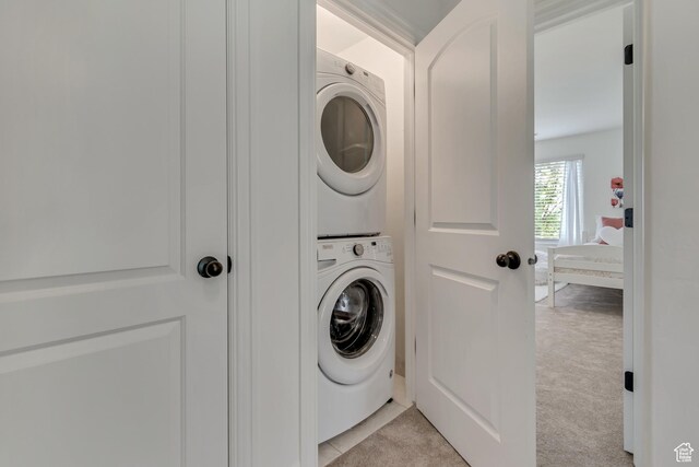 laundry room featuring stacked washer / drying machine and light colored carpet