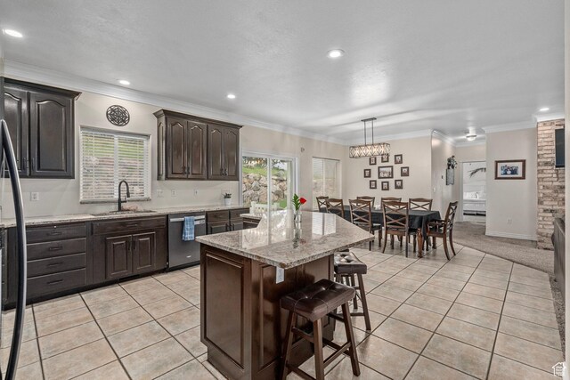 kitchen with a sink, stainless steel dishwasher, a breakfast bar area, a kitchen island, and light tile patterned floors