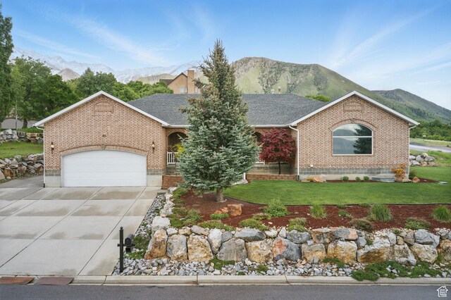 single story home with brick siding, driveway, a mountain view, a front yard, and an attached garage