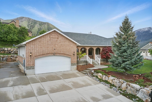 view of front facade featuring brick siding, concrete driveway, covered porch, an attached garage, and a shingled roof