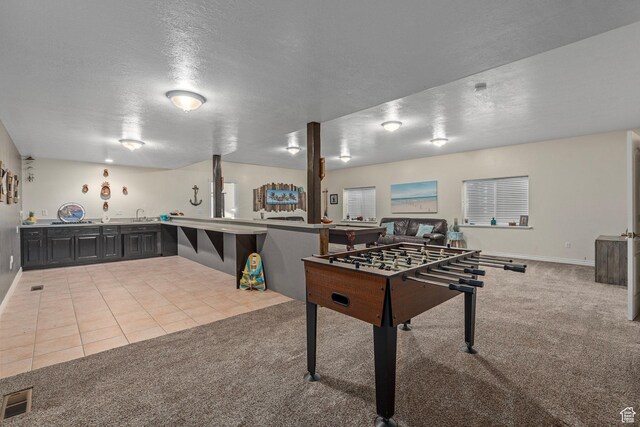 game room featuring carpet floors, a textured ceiling, a sink, tile patterned flooring, and baseboards