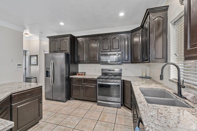 kitchen featuring appliances with stainless steel finishes, a sink, ornamental molding, light tile patterned flooring, and light stone countertops