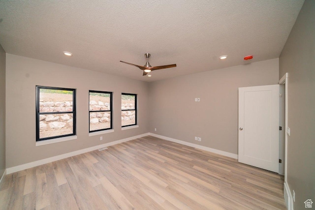 spare room featuring light wood-style floors, a textured ceiling, a ceiling fan, recessed lighting, and baseboards