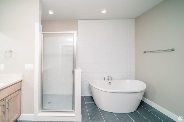 full bath with a stall shower, vanity, tile patterned flooring, a freestanding tub, and baseboards