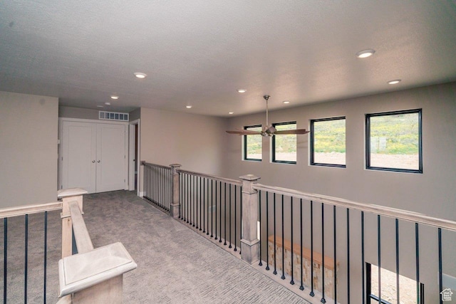 hallway with carpet floors, recessed lighting, a textured ceiling, and an upstairs landing