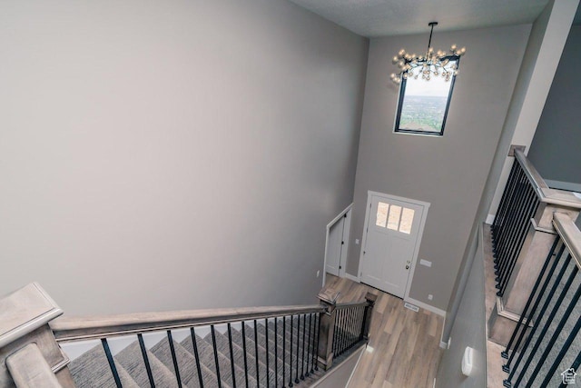 stairs with a chandelier, wood finished floors, and baseboards