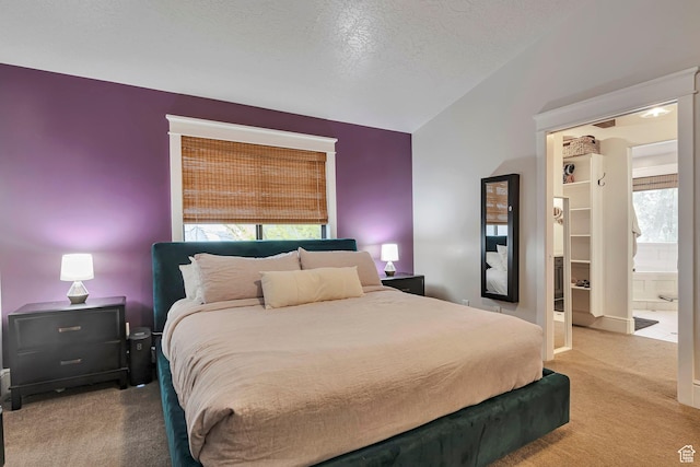 carpeted bedroom featuring vaulted ceiling, a walk in closet, and a textured ceiling