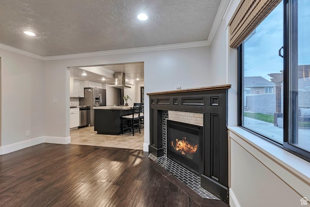 living area with light wood-style floors, ornamental molding, a tiled fireplace, recessed lighting, and baseboards