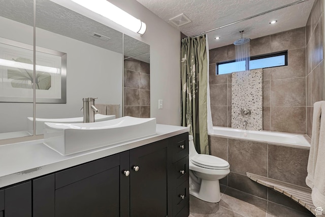 full bath with a combined bath / shower with rainfall shower, a textured ceiling, toilet, tile patterned flooring, and vanity